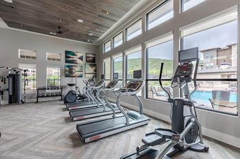 A gym with treadmills, elliptical machines, and a weight rack.